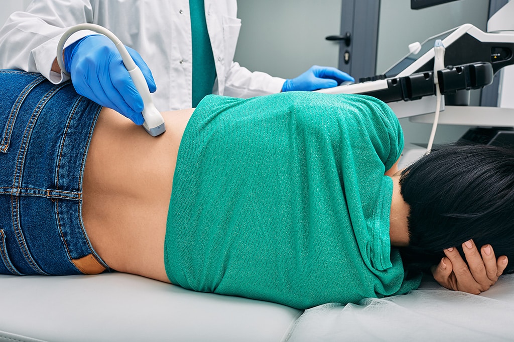 Ultrasound of kidneys. Woman patient during ultrasound examination in medical clinic lying on side, view from back