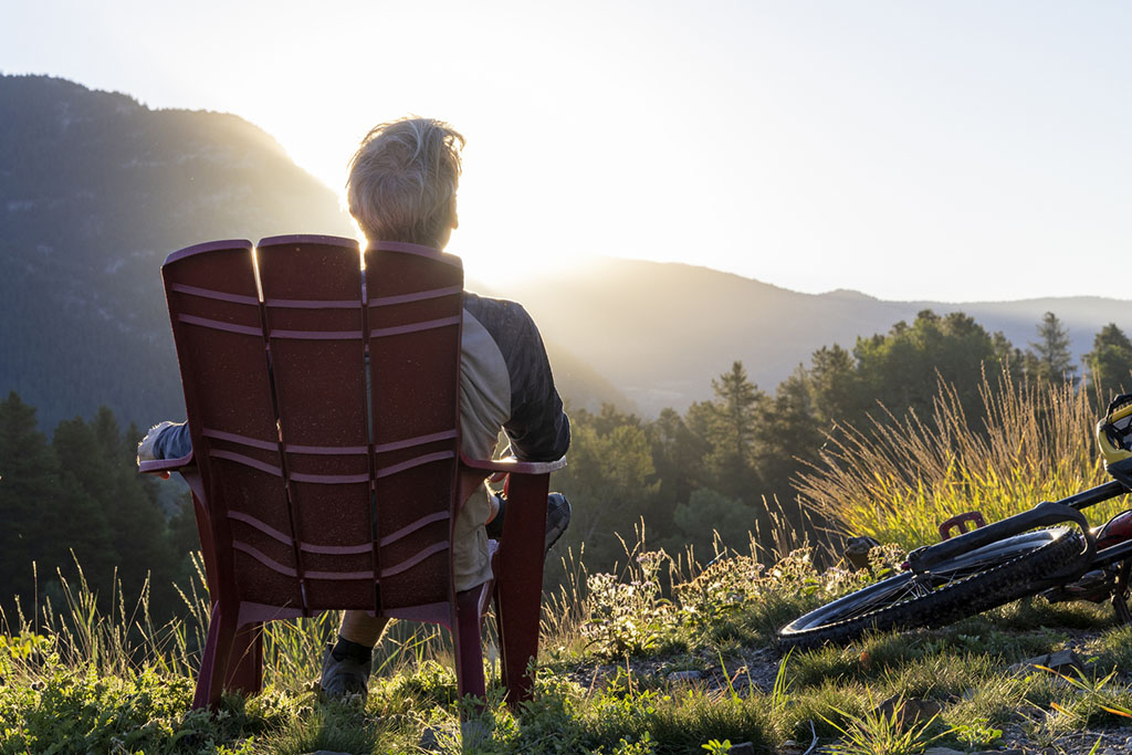 Mature man relaxes in mountain meadow at sunrise